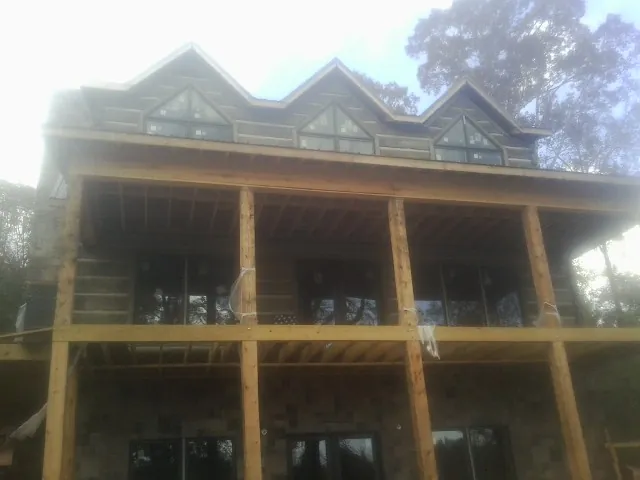 Dormers and porch framing on a large log home under construction — Roof Coating work by our crew in Ocean View
